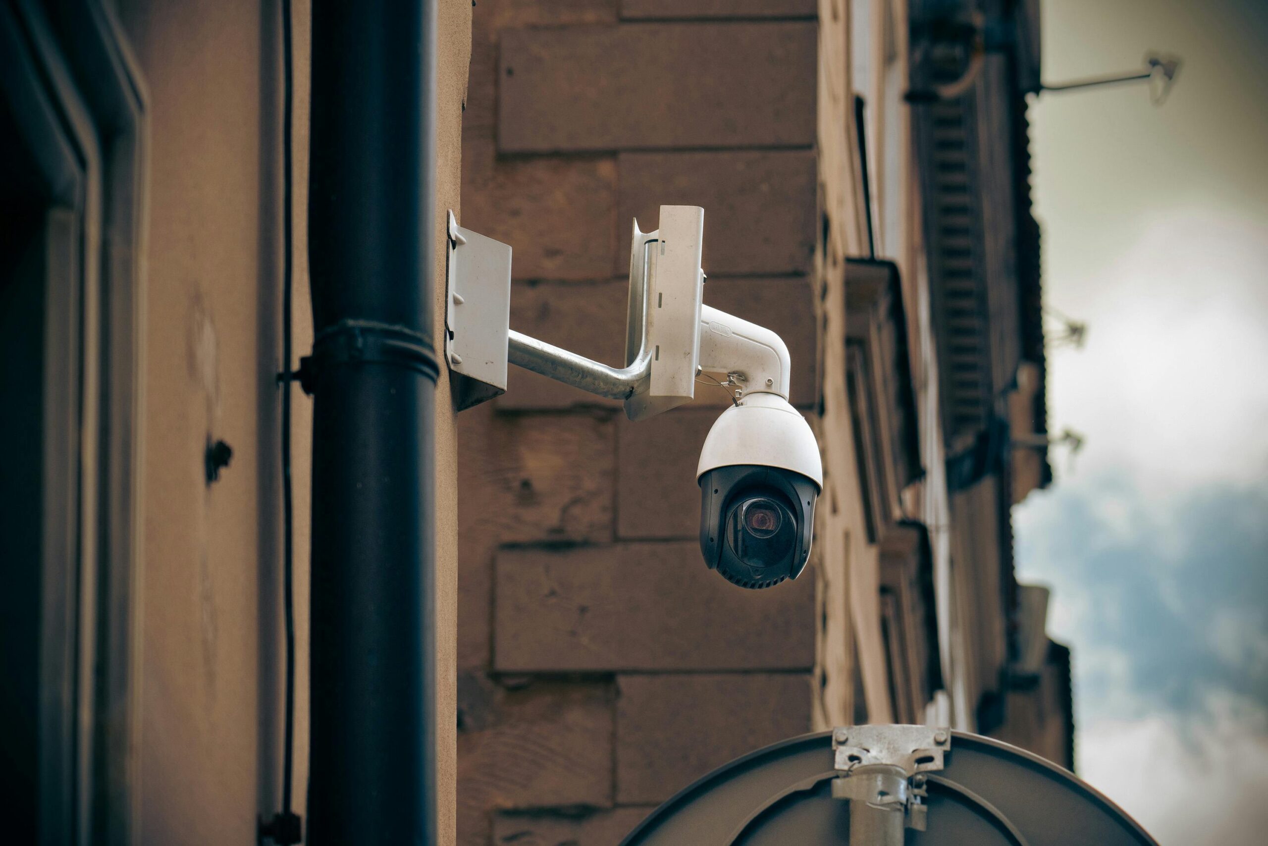 commercial-plumbing CCTV camera mounted on a building wall in an urban street setting, enhancing security.
